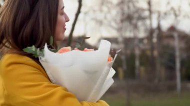 Sarı ceketli mutlu kadın güllerle dans ediyor. Sevgililer günü konsepti. Aşık bir kız. Yavaş hareket