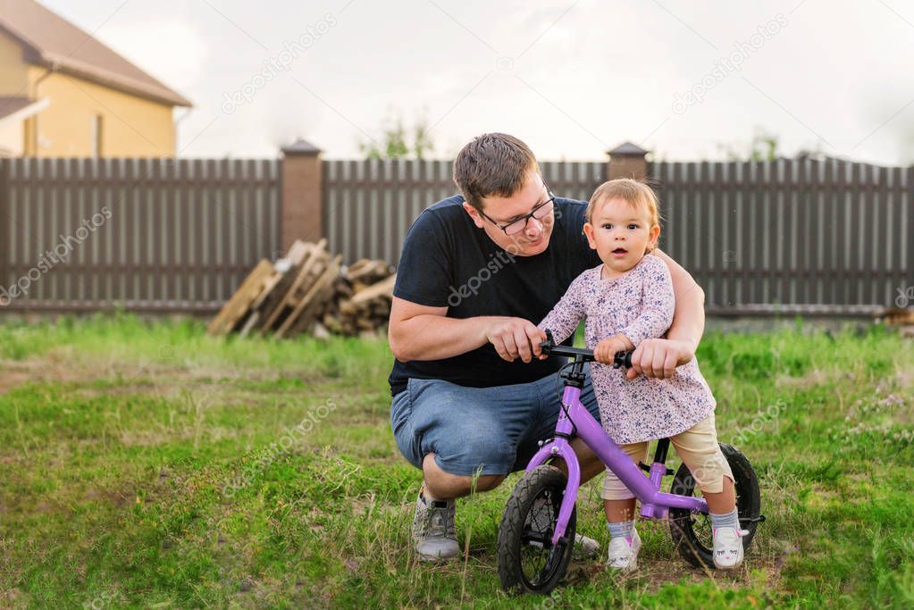 Young father spend time with Cute little one years old toddler girl child and balance bike, fathers day