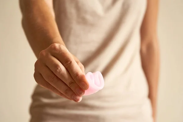 Close-up de mãos de mulher jovem segurando copo menstrual no banheiro . — Fotografia de Stock