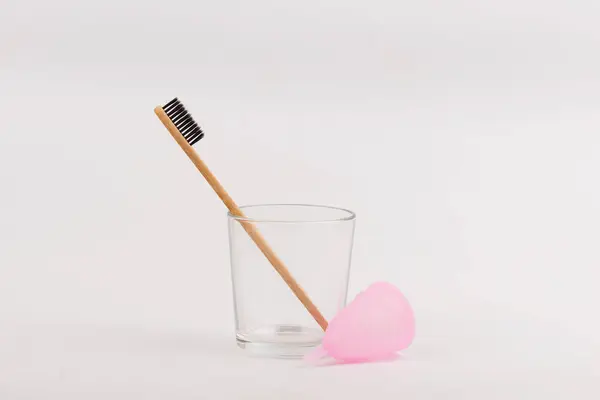 Bamboo toothbrush and menstrual cup in glass on white background. Concept zero waste — Stock Photo, Image