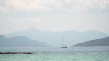 Aegina, Yunanistan'da mavi gökyüzü altında ada ile bir yelkenli. Avrupa'da yaz tatili