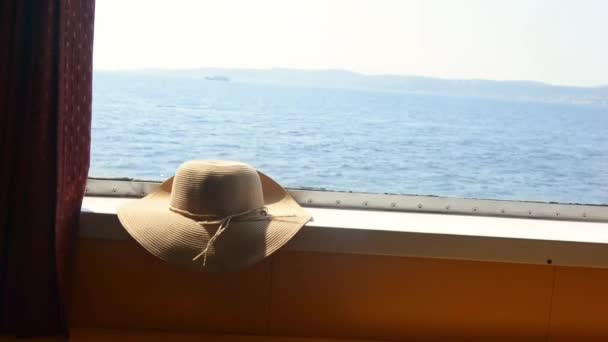 Strohhut auf dem Kabinenfenster der Fähre. Sommerreisekonzept. Urlaub — Stockvideo