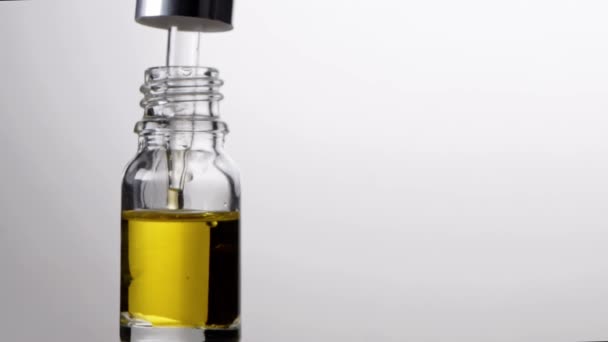 Frasco de vidrio con pipeta con gotas de aceite esencial en cámara lenta. Terapia natural — Vídeos de Stock