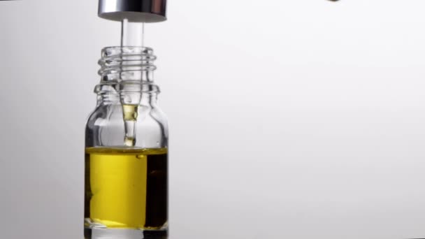 Стеклянная бутылка с пипетом с эфирными капельками масла в замедленной съемке. Естественная терапия — стоковое видео