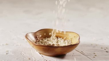 Beyaz susam yavaş çekimde plakaya düşüyor. Sağlıklı yiyecekler. 120 fps