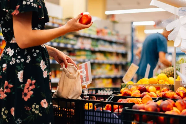 Kadın meyve ve sebze gıda pazarı seçer. Yeniden kullanılabilir çanta alışverişi. Sıfır atık