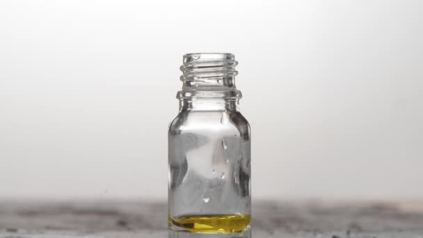 Стеклянная бутылка с пипетом с эфирными капельками масла в замедленной съемке. Естественная терапия — стоковое видео