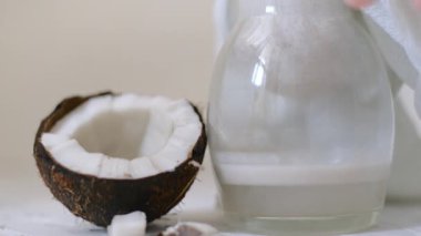 evde vegan hindistan cevizi sütü hazırlayan kadın. Süzülmek için sütü peynir bezinin içine döküyoruz. Alternatif süt