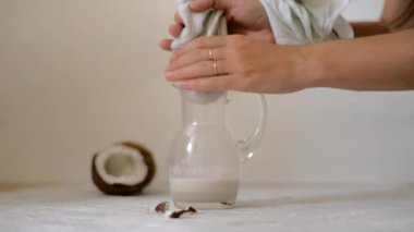 evde vegan hindistan cevizi sütü hazırlayan kadın. Süzülmek için sütü peynir bezinin içine döküyoruz. Alternatif süt