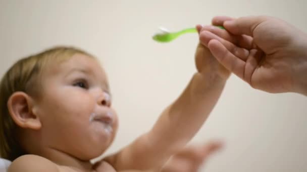 Padre alimentando al bebé con cuchara. Comida de yogur lácteo. Cara de niño graciosa. Comida para bebés desordenada — Vídeo de stock