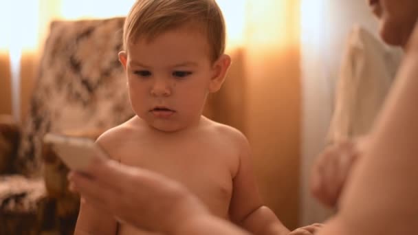 Närbild baby med morförälder titta på video på smartphone. Teknik för äldre utbildning. — Stockvideo