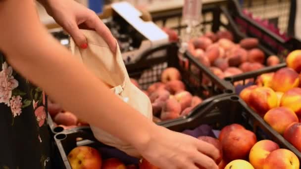 Wanita di supermarket mengambil buah segar untuk tas katun. Tidak ada alternatif plastik. sampah nol — Stok Video