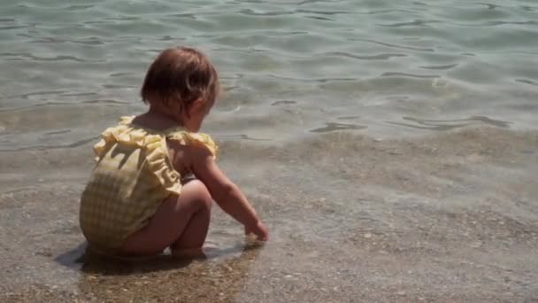 Niña en baño amarillo juega en el mar de agua. Verano con un niño pequeño en el estilo de vida de la playa — Vídeo de stock