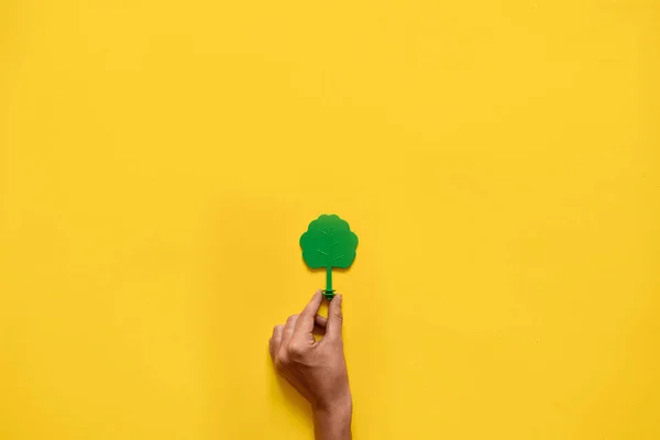 Árvore de madeira de brinquedo de plástico no fundo amarelo. Pavimentação plana mínima de ambiente ecologia — Fotografia de Stock
