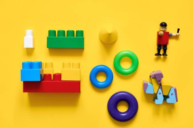 Plastik ve eko ahşap oyuncaklar Düz yatıyordu. Oyun geliştiriyor. Sarı arka plan