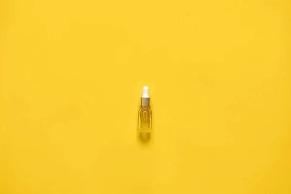 Glasflasche mit Tropfer mit Serum oder ätherischem Öl. gelber Hintergrund, natürliches medizinisches Konzept — Stockfoto