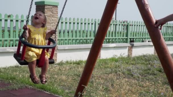 Bebé feliz en columpio en un día de verano en un parque infantil. Movimiento lento — Vídeos de Stock