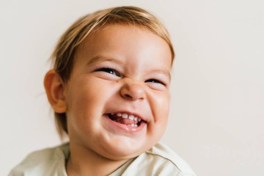 Beyaz arka planda küçük bir bebeğin heyecanlı yüzü. Saf neşe. Portreyi kapat