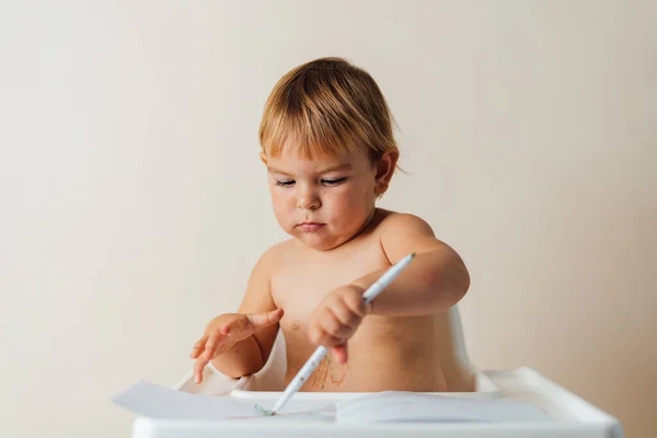 Маленька дитина малюка грає з повстяними кінчиками ручок, малюючи барвисті лінії на папері. Креативна освіта — стокове фото