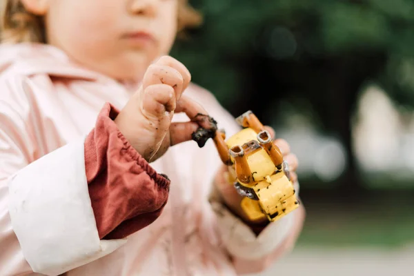 Pink raincoat dirty in mud. Hands of the child. Spring autumn outdoors activity for kids. Carefree childhood