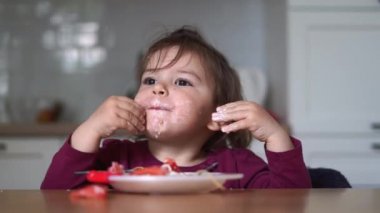 Küçük kız evde domatesli ve kremalı spagetti yiyor. dağınık bebek yemeği zamanı.