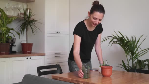 Chica milenaria trabajando desde casa en una sala de plantas. Floristería independiente, joven propietario de negocios, jardinería en el hogar — Vídeo de stock