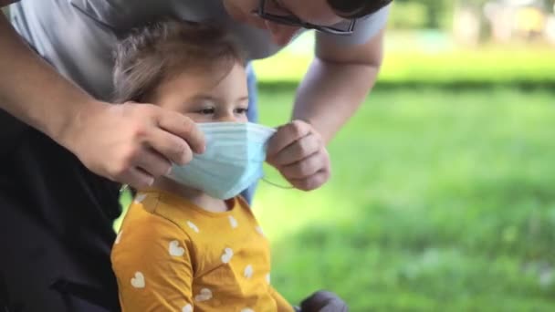 밖에 나가 의료용 마스크를 쓴 행복 한 꼬마 소녀. 새로운 정상적 인 여름 2020. 취학전의 어린이 — 비디오