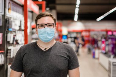 Beyaz adam tıbbi maskeli giysiler için alışveriş yapıyor. Yeni normal kavram. 
