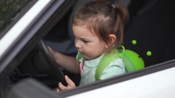 Bébé tout-petit fille assise sur le siège avant de la voiture avec volant. Retour à l'école — Video