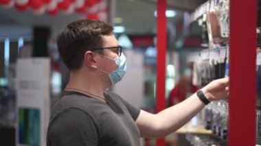 Beyaz adam tıbbi maskeli giysiler için alışveriş yapıyor. Yeni normal kavram. 