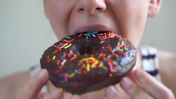 Mulher branca a comer donut. Um tiro de perto. Com fome, junk food — Vídeo de Stock