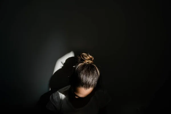 Menina sentada sozinha no bolso da luz solar no quarto escuro. conceito de saúde mental — Fotografia de Stock