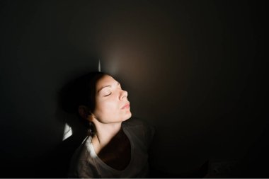 Karanlık odada güneş ışığında tek başına oturan bir kız. ruh sağlığı kavramı