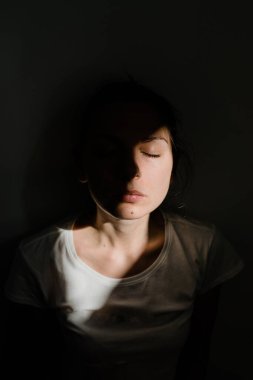 Karanlık odada güneş ışığında tek başına oturan bir kız. ruh sağlığı kavramı