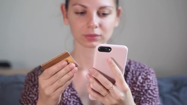 Kaukasiska kvinna hemma med telefon och kreditkort. Internetbank. personlig budget. — Stockvideo