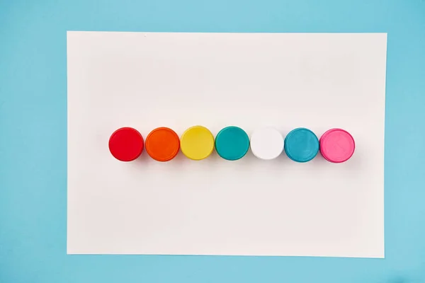 Draufsicht auf regenbogenfarbene Farbflaschen auf weißer Leinwand — Stockfoto