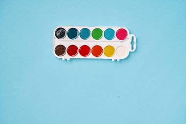 Mavi arka planda suluboya resminin üst görüntüsü. Okula geri dön.