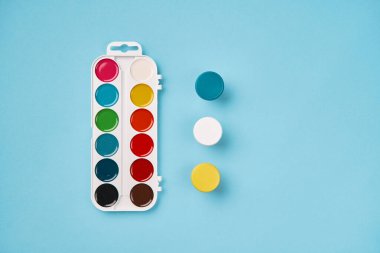 Mavi arka planda suluboya resminin üst görüntüsü. Okula geri dön.