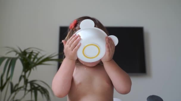 Małe dziecko je i pije mleko z miski. Czas obiadu — Wideo stockowe