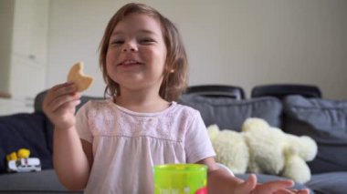 Küçük kız kurabiye yiyip meyve suyu içiyor. Çocuk için abur cubur. Ev hayatı