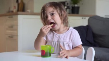 Küçük kız kurabiye yiyip meyve suyu içiyor. Çocuk için abur cubur. Ev hayatı