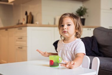 Küçük kız kurabiye yiyip meyve suyu içiyor. Çocuk için abur cubur. Ev hayatı
