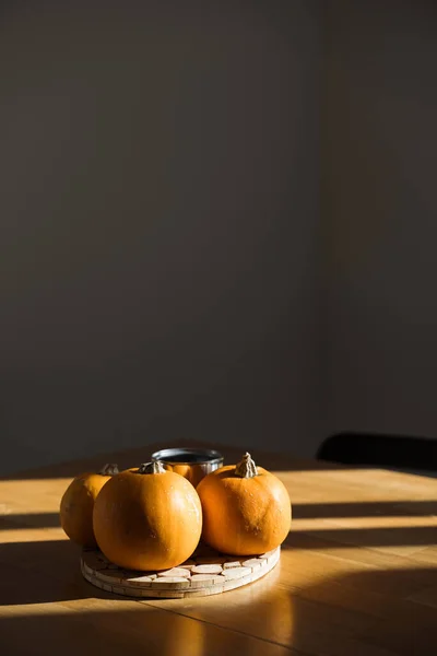 Kürbisdekor auf Holztisch zu Hause im Sonnenlicht. Schatten der Herbstsonne. Halloween — Stockfoto
