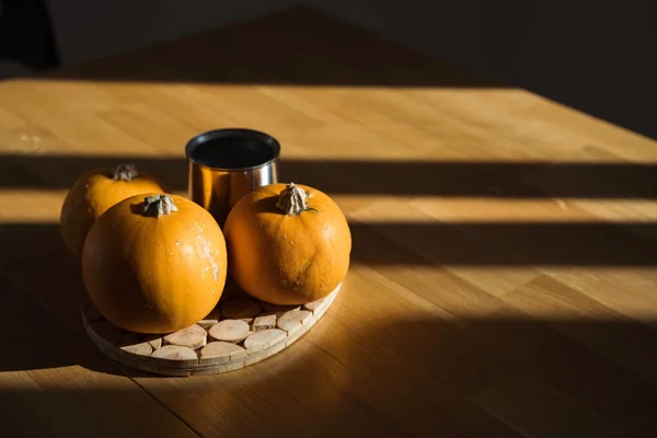 Decoração de abóbora na mesa de madeira em casa à luz do sol. Sombras de sol de outono. Halloween. — Fotografia de Stock