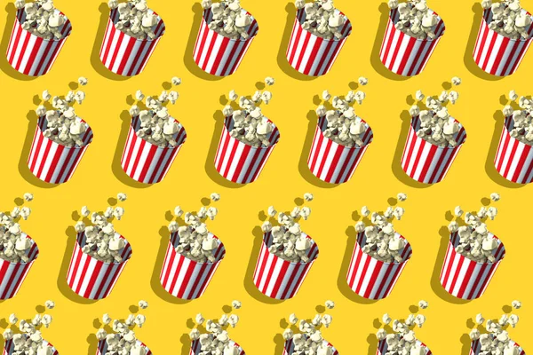 Pattern of popcorn retro boxes on yellow background. Harsh shadow. Cinema theatre food