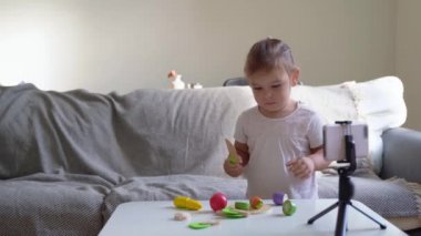 Kız çocuk internette tahta oyuncakların videosunu gösteriyor. Etki alanı, oyunlar günlüğü