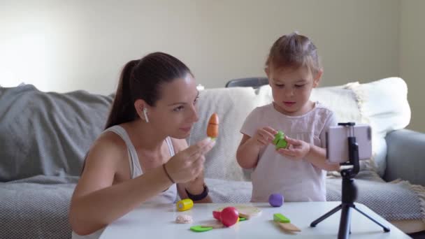 Мати з дитиною транслює онлайн відео про розпакування дерев'яних іграшок. Інфлюенсерська професія, матуся блог — стокове відео
