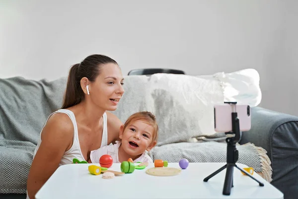 Matka z dzieckiem streaming wideo online z rozpakowywania drewnianych zabawek. Influencer zawód, mama blog — Zdjęcie stockowe