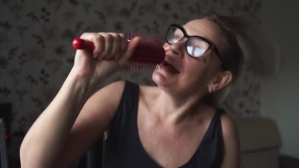 Běloška bláznivá žena středního věku doma zpívá na kartáči na vlasy. Šťastní pozitivní dospělí lidé doma. — Stock video