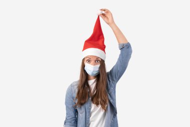 Telefon maskeli ve Noel Baba şapkalı genç bir kadın. Karantinada Noel alışverişi.